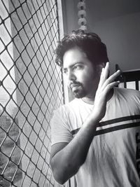 Portrait of young man looking through fence