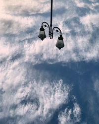 Low angle view of lighting equipment hanging against sky