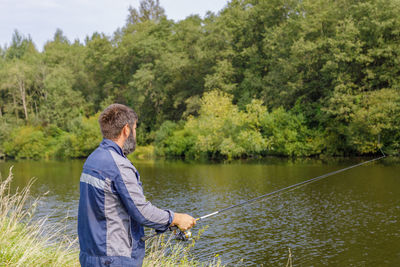 A man with a beard is fishing on the river.