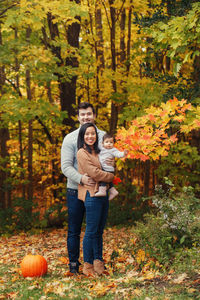 Full length of family standing in forest during autumn