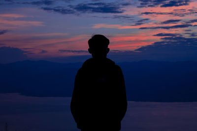 Rear view of silhouette man standing against sky during sunset