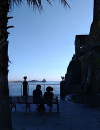 People sitting at town square against clear blue sky