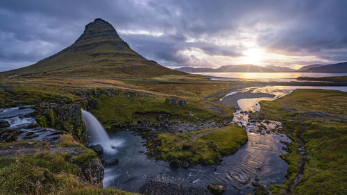 Scenic view of waterfall against sky during sunset