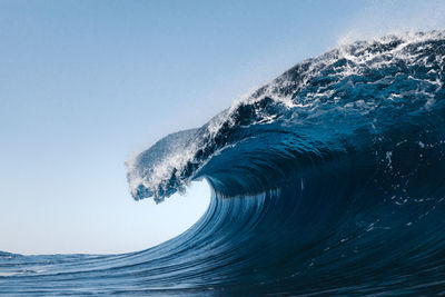 Sea wave splashing against clear blue sky