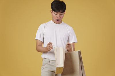 Full length of boy standing against yellow background