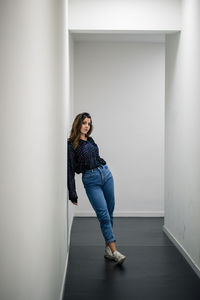 Portrait of woman leaning against wall in corridor 