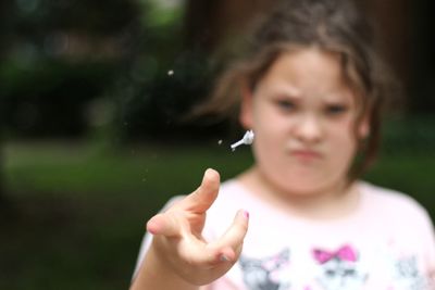 Portrait of girl throwing flower outdoors