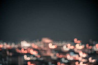 Defocused image of illuminated city against sky at night