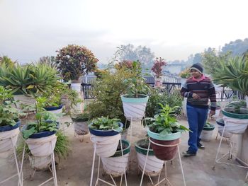 People standing by potted plants on table against sky
