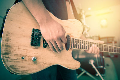 Midsection of man playing guitar