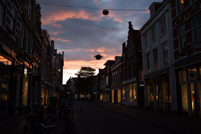 Street in city against sky at sunset