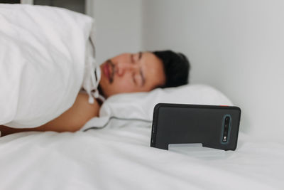 Young woman using mobile phone while lying on bed at home