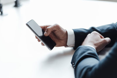 Businessman using smart phone on desk in office