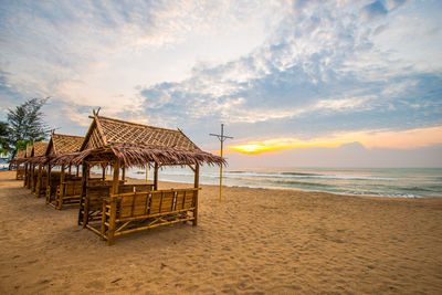 Lifeguard hut on beach against sky during sunset