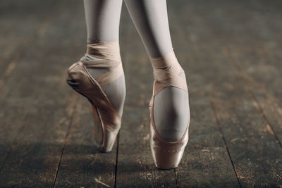 Low section of woman in ballet shoe dancing on floorboard