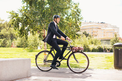 Full length of businessman riding bicycle in park