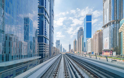 Railroad tracks amidst buildings in city against sky