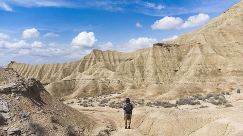 Panoramic view of the colored stone desert and traveler on his back walking on the rocks