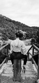 Rear view of woman standing on walkway against sky