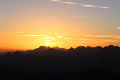 Scenic view of silhouette mountains against orange sky