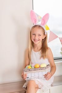 Portrait of smiling young woman holding gift against white background