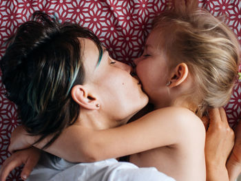 Close-up of woman kissing daughter while sleeping on bed