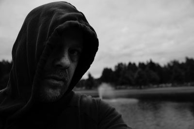 Close-up portrait of man with lake against sky