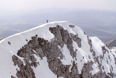 Distant view of person standing snowcapped mountain