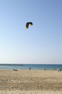 People enjoying at beach against clear sky