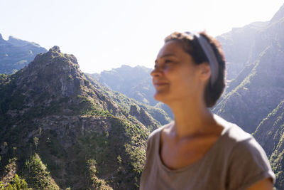 Mid adult woman looking away against mountains against sky