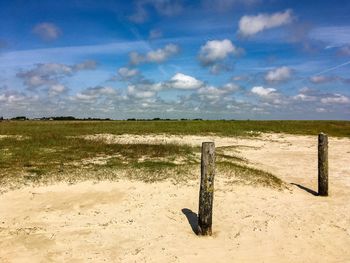 Wooden posts on field against sky