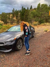 Portrait of teenage boy with car on road