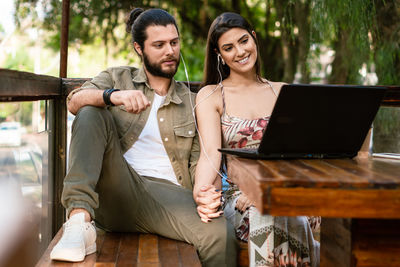 Portrait of smiling woman using laptop while sitting on sofa at home