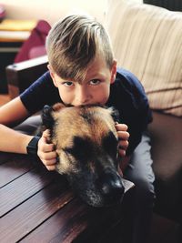 Portrait of cute boy with dog sitting at home