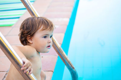 Portrait of cute girl sitting on swimming pool