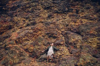 Woman with umbrella walking on rock