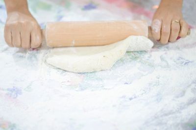Cropped image of woman rolling dough on table