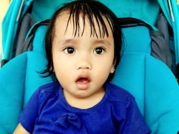 Close-up portrait of cute baby girl sitting in stroller