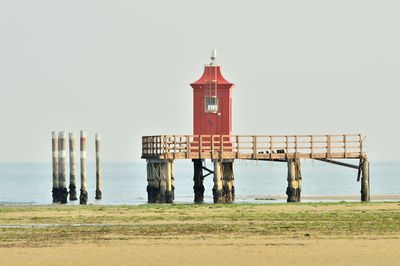 Lighthouse by sea against clear sky