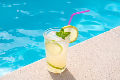 Glass of water on table at swimming pool