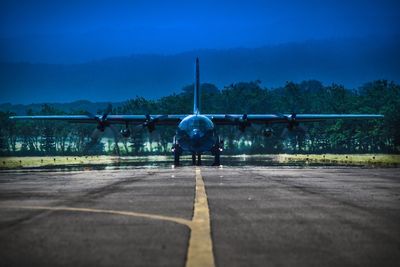 Airplane at airport runway against sky