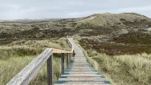 View of wooden boardwalk leading towards mountains