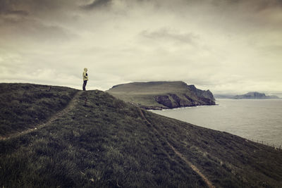 Man standing on hill while looking at sea