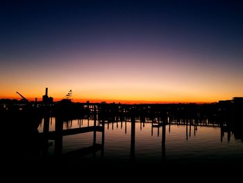 Silhouette built structure by sea against clear sky during sunset