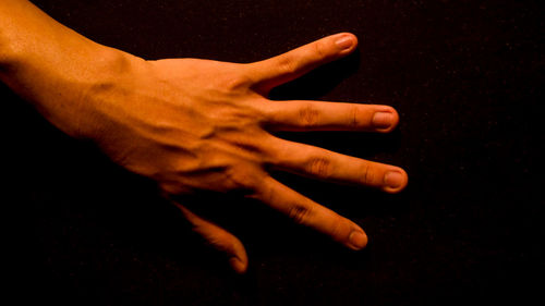 Close-up of human hand against black background