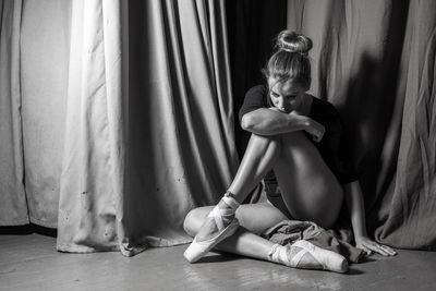 Thoughtful ballerina sitting on floor