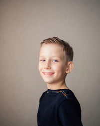 Portrait of smiling boy against gray background