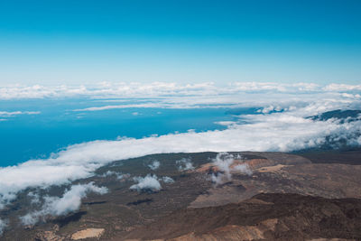 Clouds over volcanic landscape against blue sky