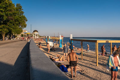 People on beach against clear blue sky