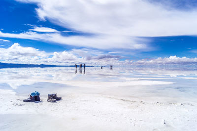 Distant view of people on salt lake against cloudy sky